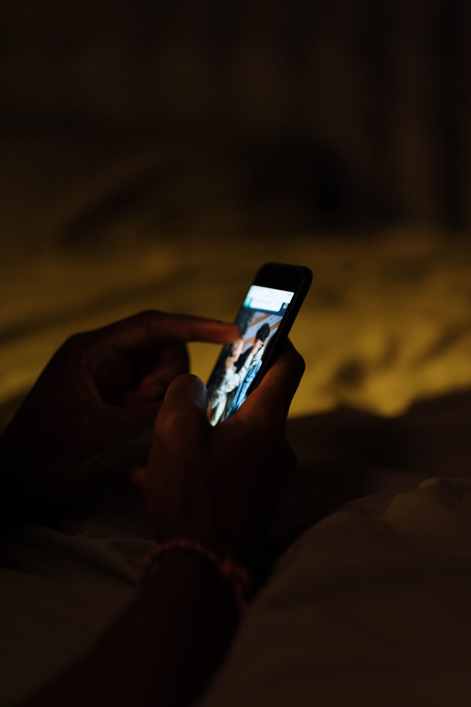 Mano sosteniendo un smartphone en penumbra